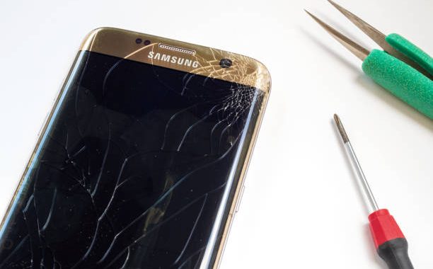 Chiangrai, Thailand: September 20, 2017 - Smart phone Samsung Galaxy S7 edge broken and cracked screen with screwdriver and tweezers prepairing to repair on white background